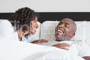 Happy couple cuddling in bed and laughing