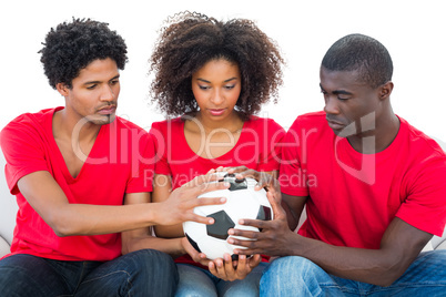 Football fans in red holding ball together