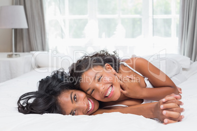 Smiling mother and daughter posing together on bed