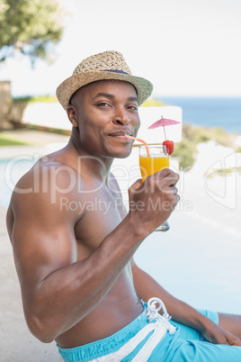 Handsome shirtless man relaxing with cocktail poolside