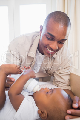 Happy father playing with his baby son in crib