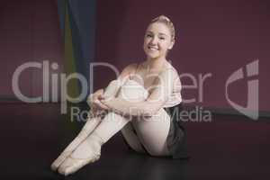 Pretty ballerina sitting and smiling at camera