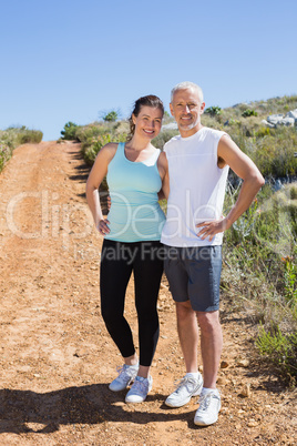 Fit smiling couple jogging down mountain trail