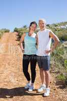 Fit smiling couple jogging down mountain trail