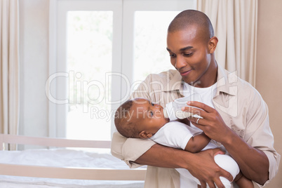 Happy father feeding his baby boy a bottle