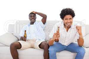 Nervous sports fans sitting on the couch with beers