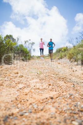 Fit couple jogging down mountain trail