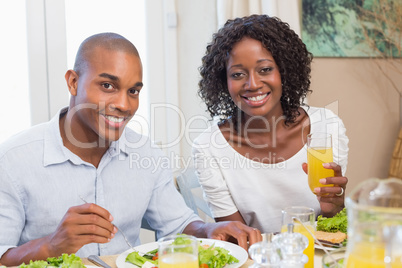 Couple enjoying a healthy meal together smiling at camera