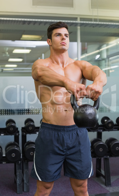 Muscular man lifting kettle bell in gym Muscular man lifting kettle bell in gym