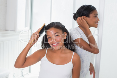 Cute daughter brushing hair with her mother