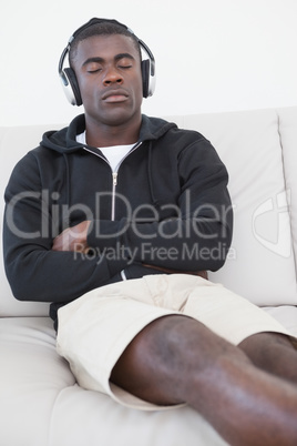 Casual man sitting on sofa enjoying music with eyes closed