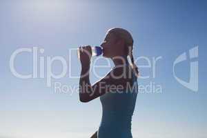 Fit woman drinking from water bottle