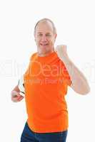 Mature man in orange tshirt cheering holding football