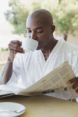 Handsome man in bathrobe having coffee outside