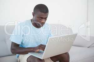 Casual man sitting on sofa using laptop