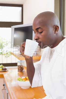 Happy man in bathrobe drinking coffee