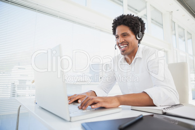 Happy businessman working at his desk wearing headset