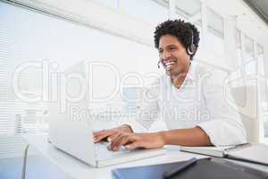 Happy businessman working at his desk wearing headset