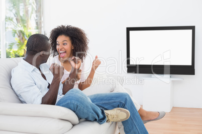 Couple sitting on couch together watching tv