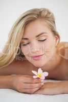 Beautiful blonde lying on massage table smelling flower