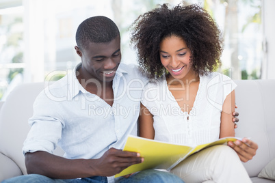 Attractive couple relaxing on couch together looking at photo al