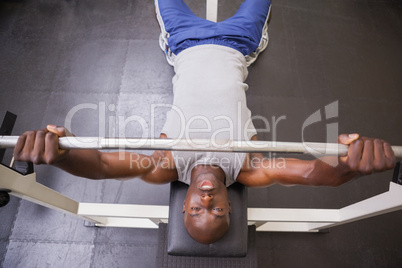 Muscular man lifting barbell in gym