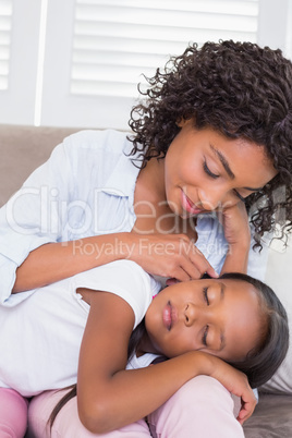 Pretty mother sitting on the couch with her sleeping daughter