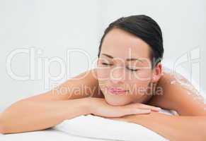 Peaceful brunette lying with salt scrub on back