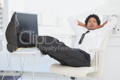 Businessman relaxing in his swivel chair with feet up