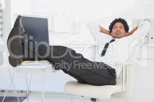 Businessman relaxing in his swivel chair with feet up