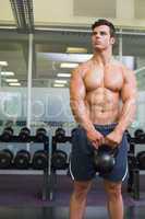 Muscular man lifting kettle bell in gym