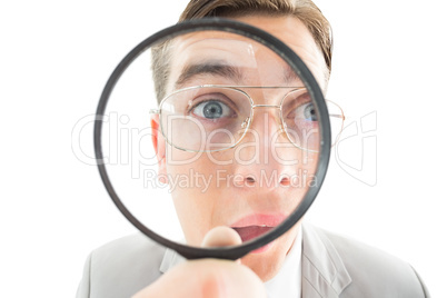 Geeky businessman looking through magnifying glass