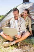 Outdoorsy couple looking at the laptop outside tent