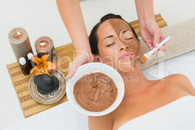 Peaceful brunette getting a mud facial applied
