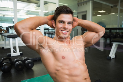 Smiling shirtless muscular man in gym