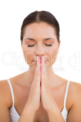 Peaceful brunette meditating with hands together