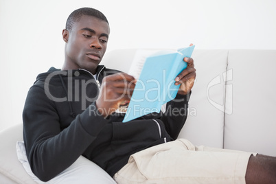 Casual man sitting on his sofa reading a book Casual man sitting on his sofa reading a book