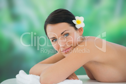 Beautiful brunette relaxing on massage table smiling at camera