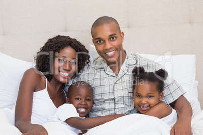 Happy family cuddling in bed together