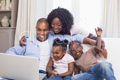 Happy family on the couch together using laptop