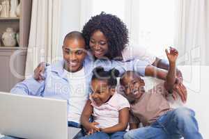 Happy family on the couch together using laptop