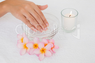 Hand in bowl along flowers and candle