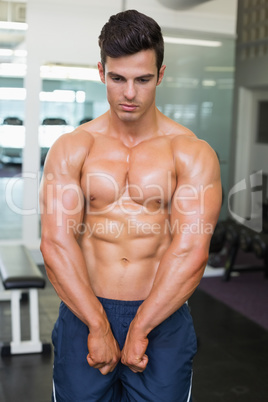 Shirtless muscular man flexing muscles in gym