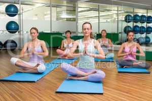 Smiling yoga class in lotus pose in fitness studio