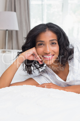 Pretty woman smiling at camera lying on bed