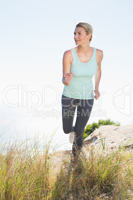 Fit blonde jogging on mountain trail