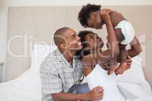 Happy parents with baby girl on the bed