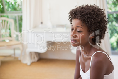 Thoughtful woman sitting on bed