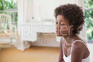 Thoughtful woman sitting on bed