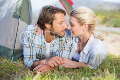 Attractive couple lying in their tent about to kiss